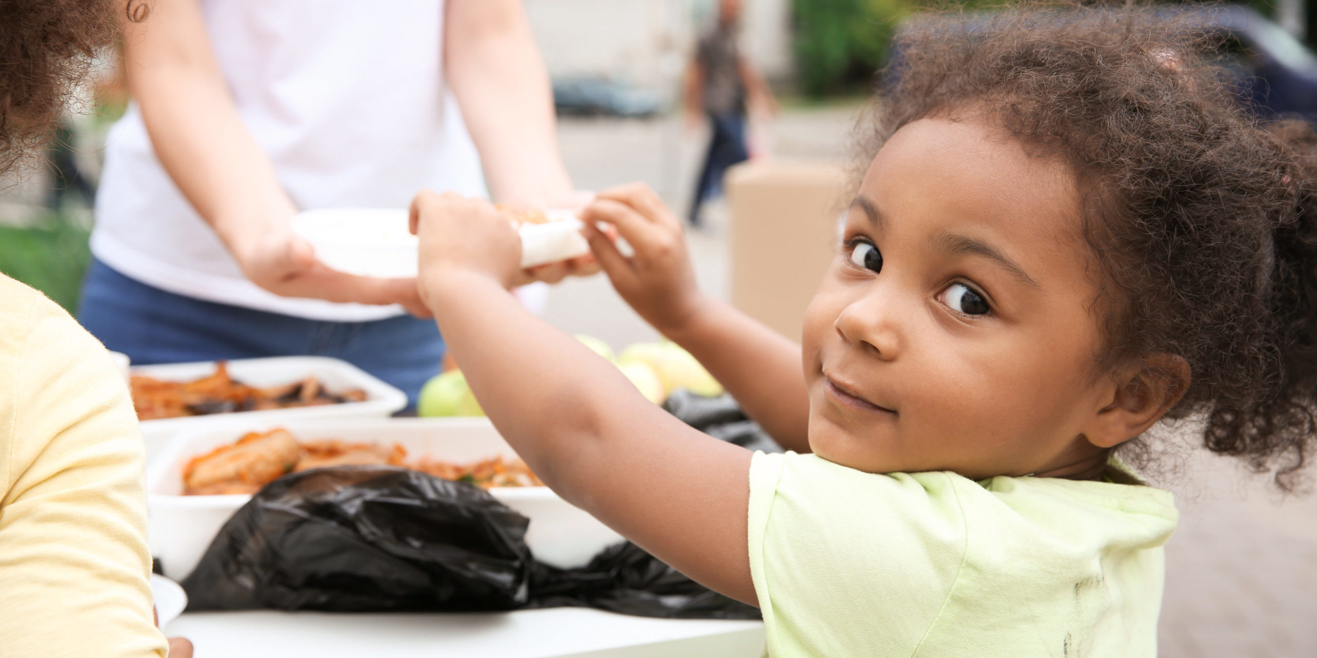 Volunteer sharing food with poor African child outdoors