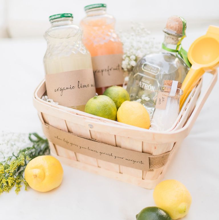 A simple wood basket filled with different sized bottles. Each bottle is filled with different juices. There are also lemons and limes inside the basket.It is a margarita gift basket for Mother's Day.