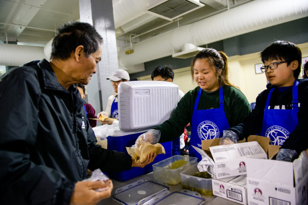 SVdPLA volunteers in blue aprons serving food at the homeless shelter
