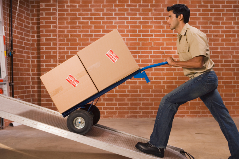 Man uses a dolly to load boxes into a large truck.