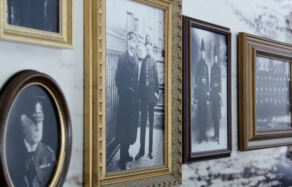 Brown and gold picture frames hold black and white vintage photos of various men